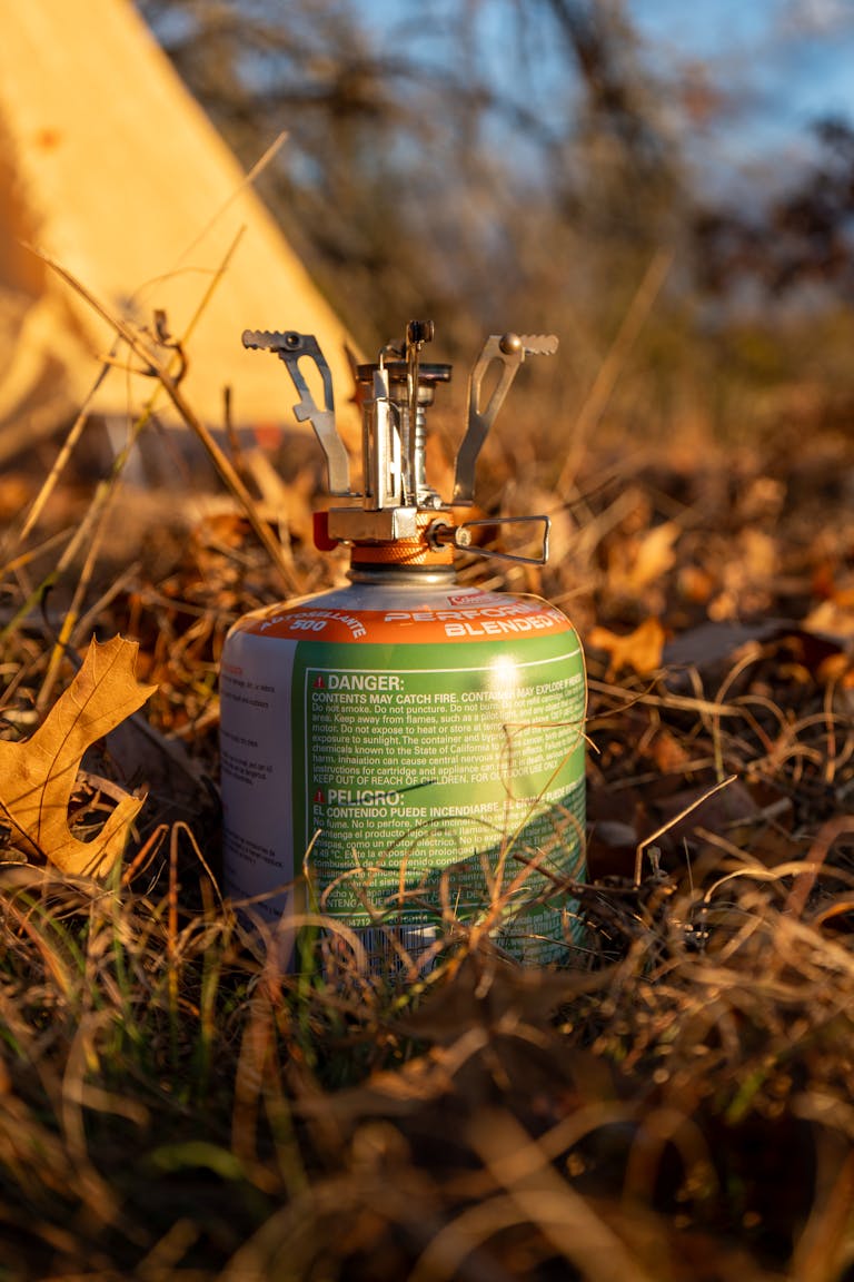 A portable camping stove setup in an autumn forest, ideal for backpacking and outdoor cooking enthusiasts.